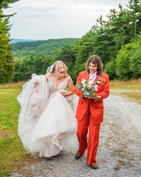 bride and groom in orange suit walking down mountain path