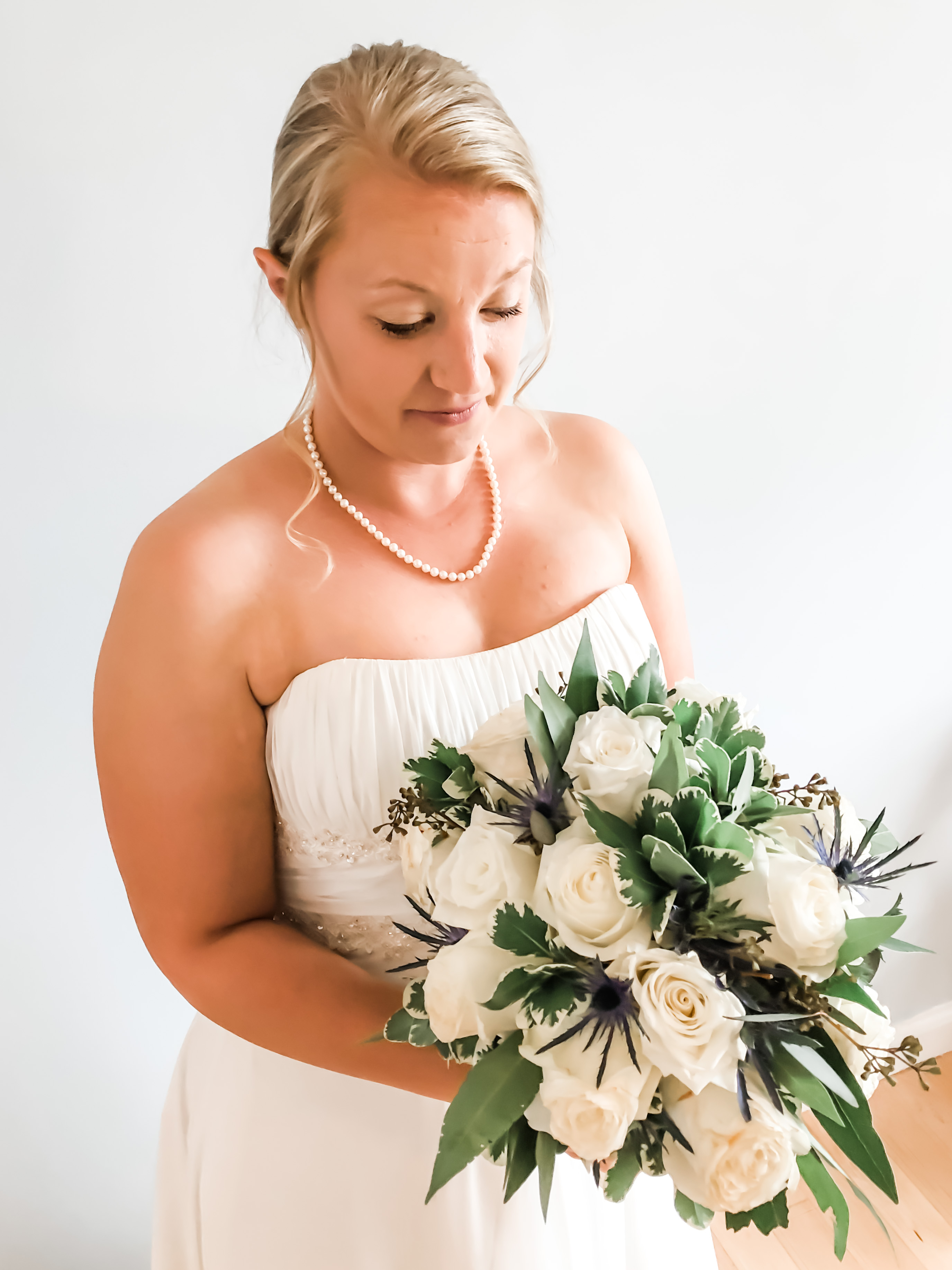 bride holding white bridal bouquet with greenery