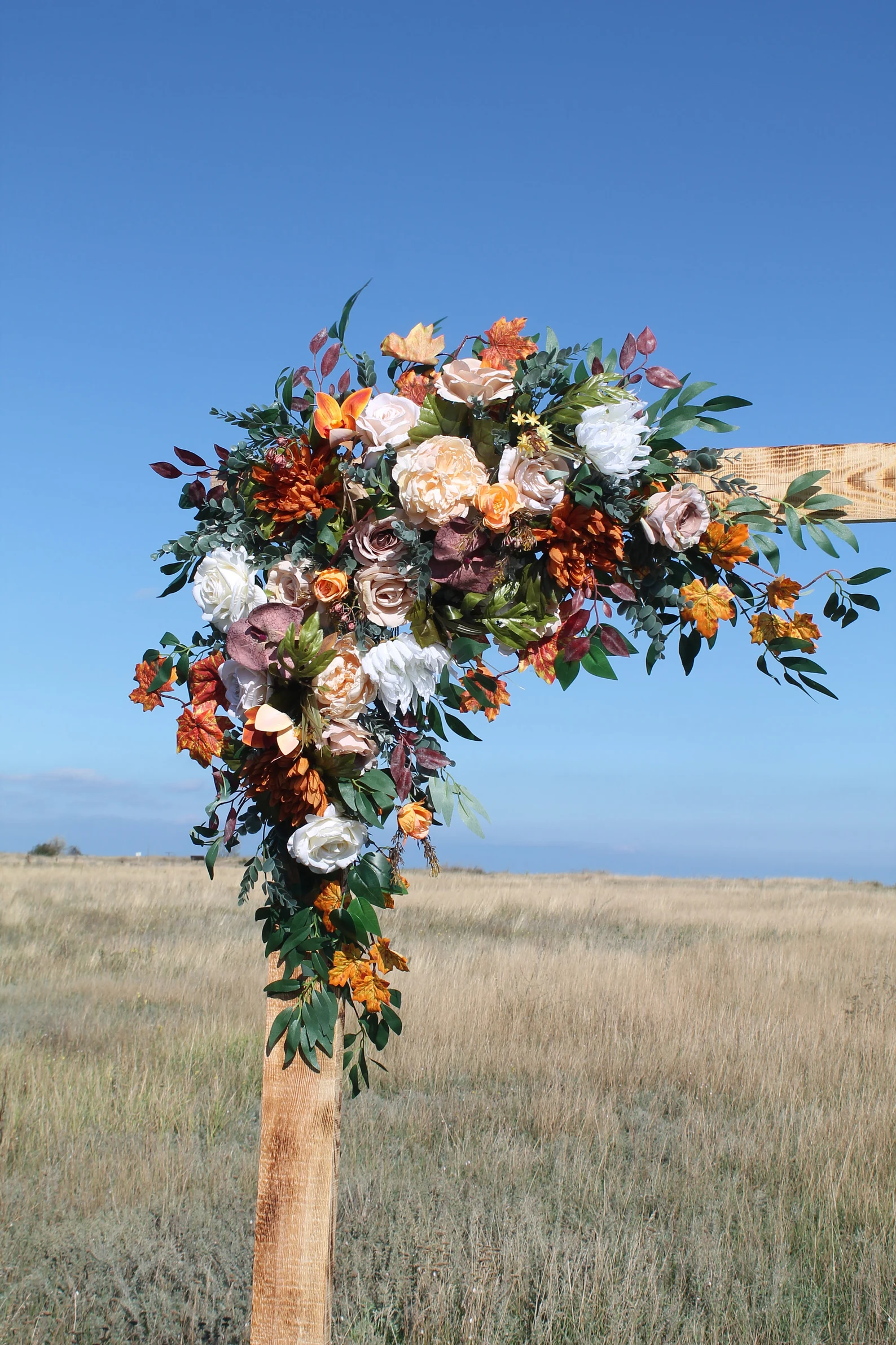 orange and white flower arrangement on wooden wedding arch