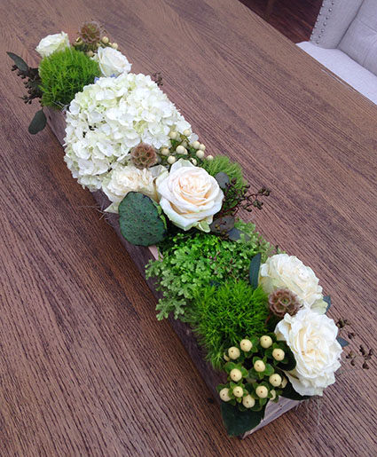 white and green floral centerpiece in wooden container