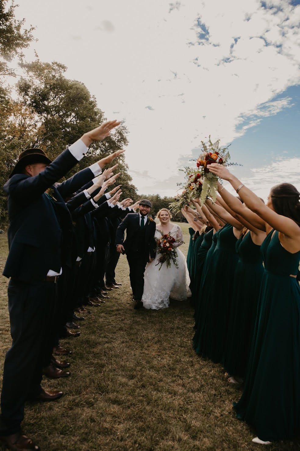 bride and groom walking between wedding party's arms