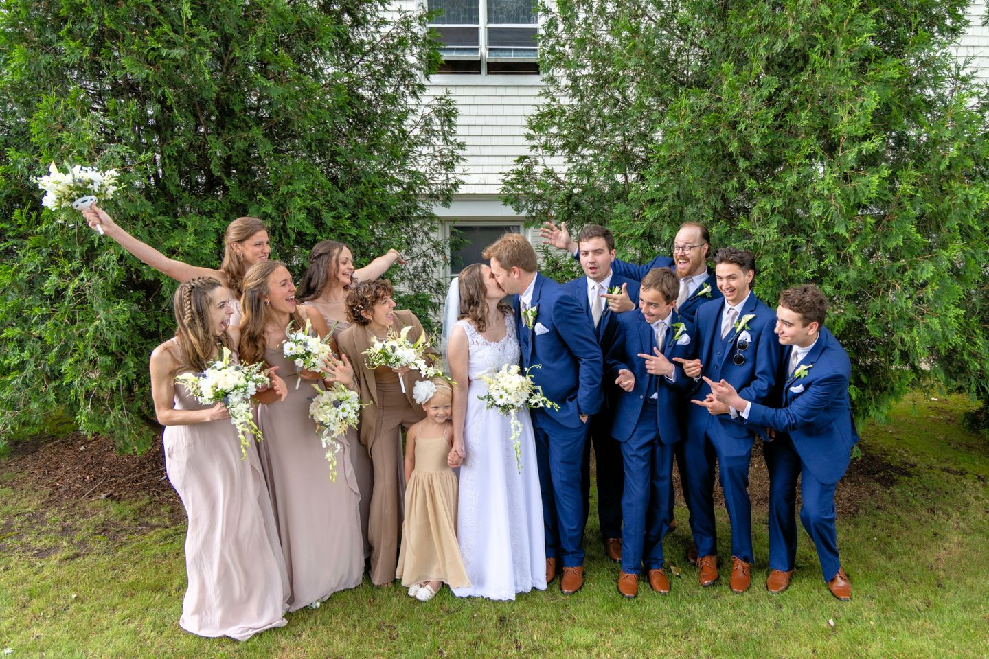 bride and groom kissing while wedding party cheers