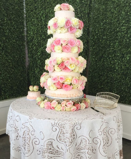 five tier wedding cake covered in pink and yellow roses